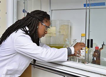 St. John’s student pours liquid into a triangular beaker while conducting health science research.