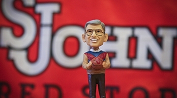 Bobblehead of Lou Carnesecca infront of St. John's flag