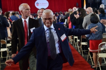 Employee smiling while walking down aisle at 2024 Employee Recognition Convocation