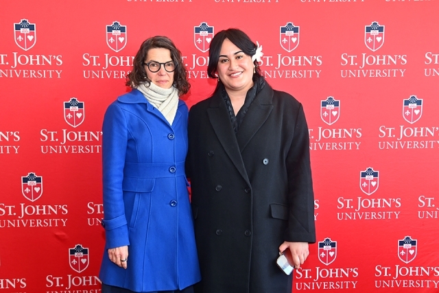 Two women standing in front of St. John's University step and repeat