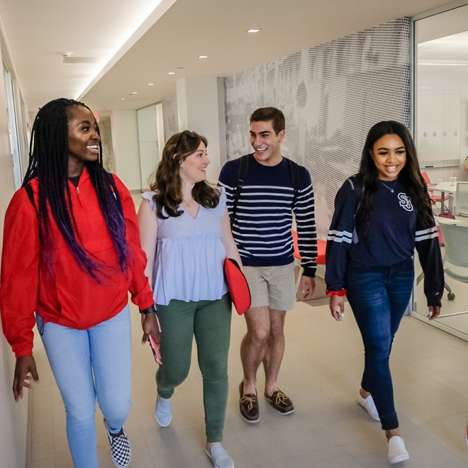 Group of students walking down the hallway discussing their M.B.A. studies.